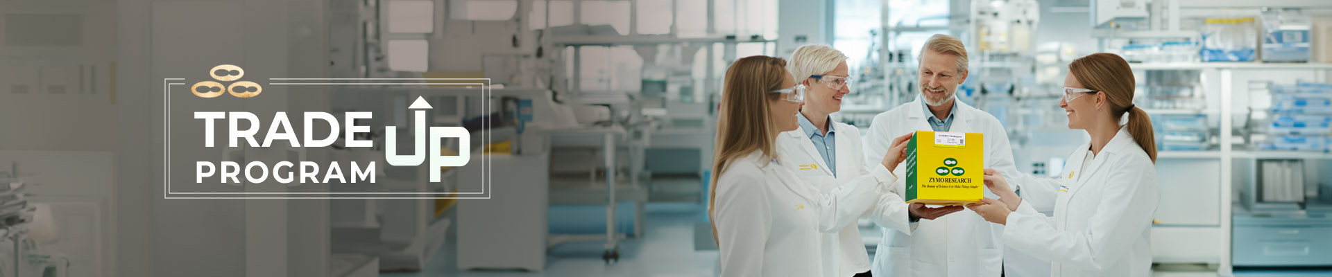 Four scientists wearing lab coats and safety goggles are gathered in a modern laboratory. They are smiling and holding a green and yellow Zymo Research box. The text 'Trade Up Program' is displayed prominently on the left with a clean, professional design