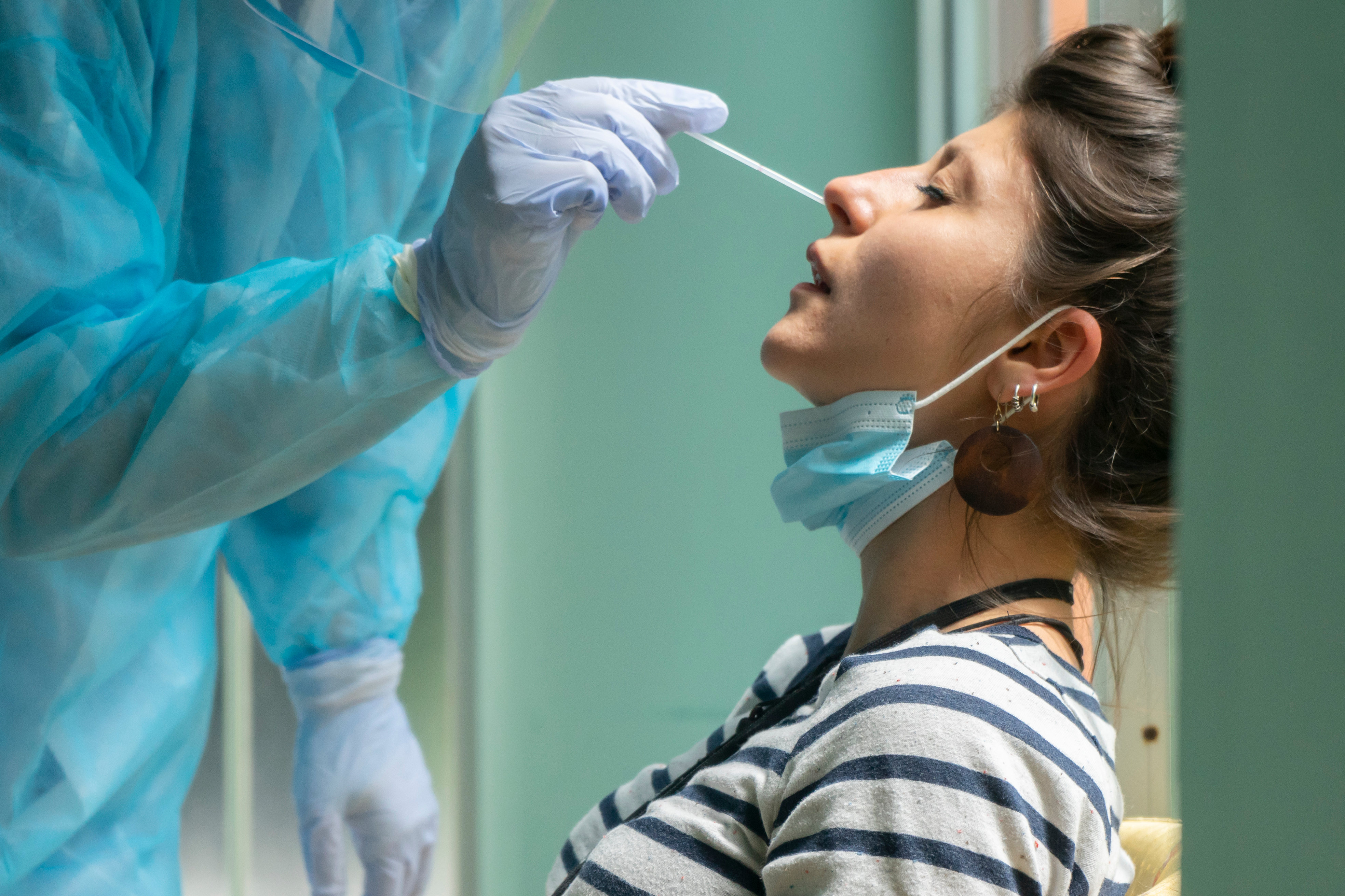 A nurse collecting a nasal swab sample from a patient.