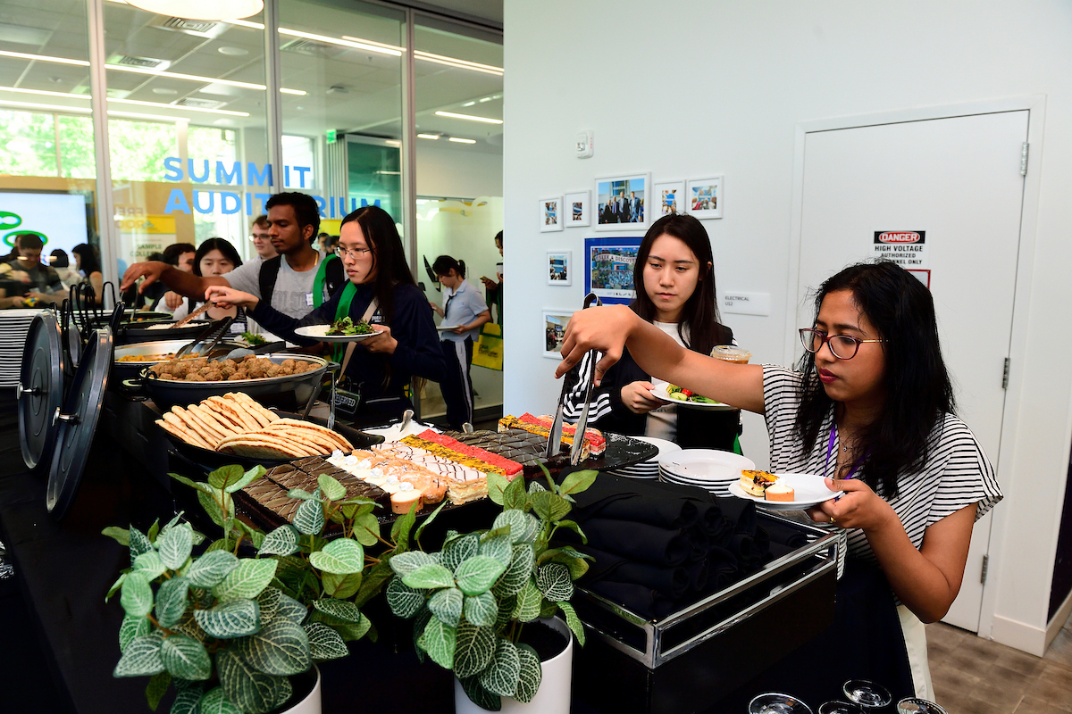 Attendees serve themselves food from a buffet table with various dishes and desserts during the BioFestival event.