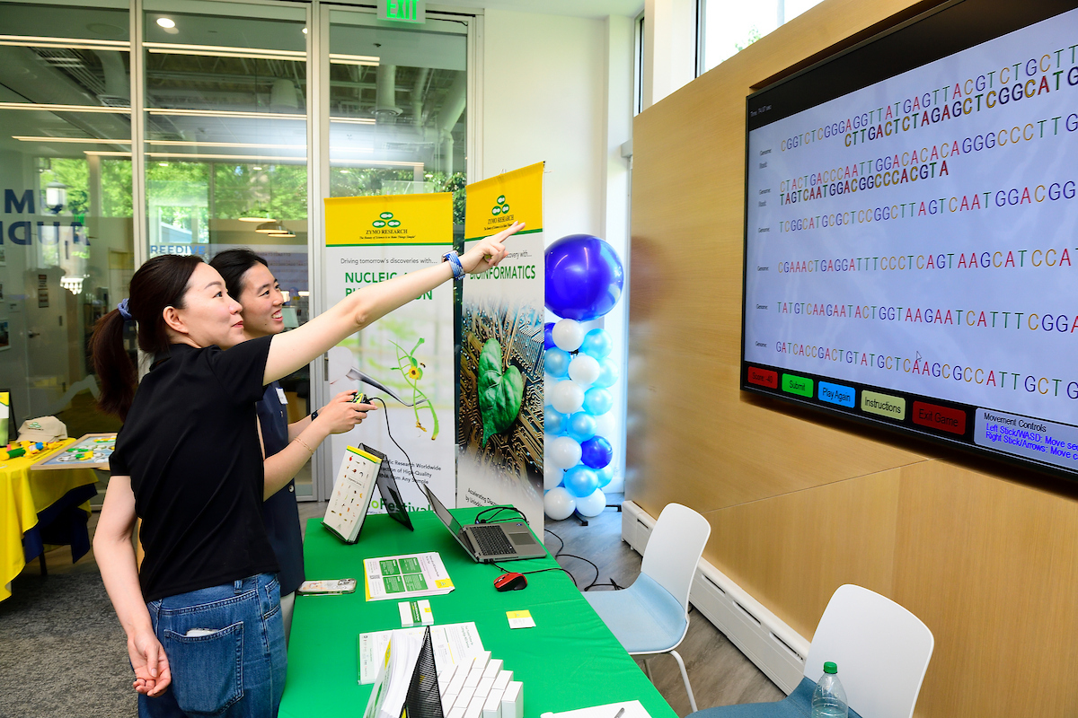An attendee plays an interactive DNA sequencing game at a Zymo Research booth during the BioFestival event.