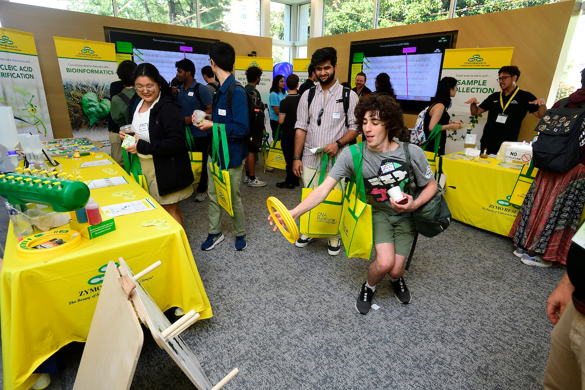 Attendees participate in a plasmid ring toss game and explore interactive science exhibits at the Zymo Research booth during the BioFestival event.