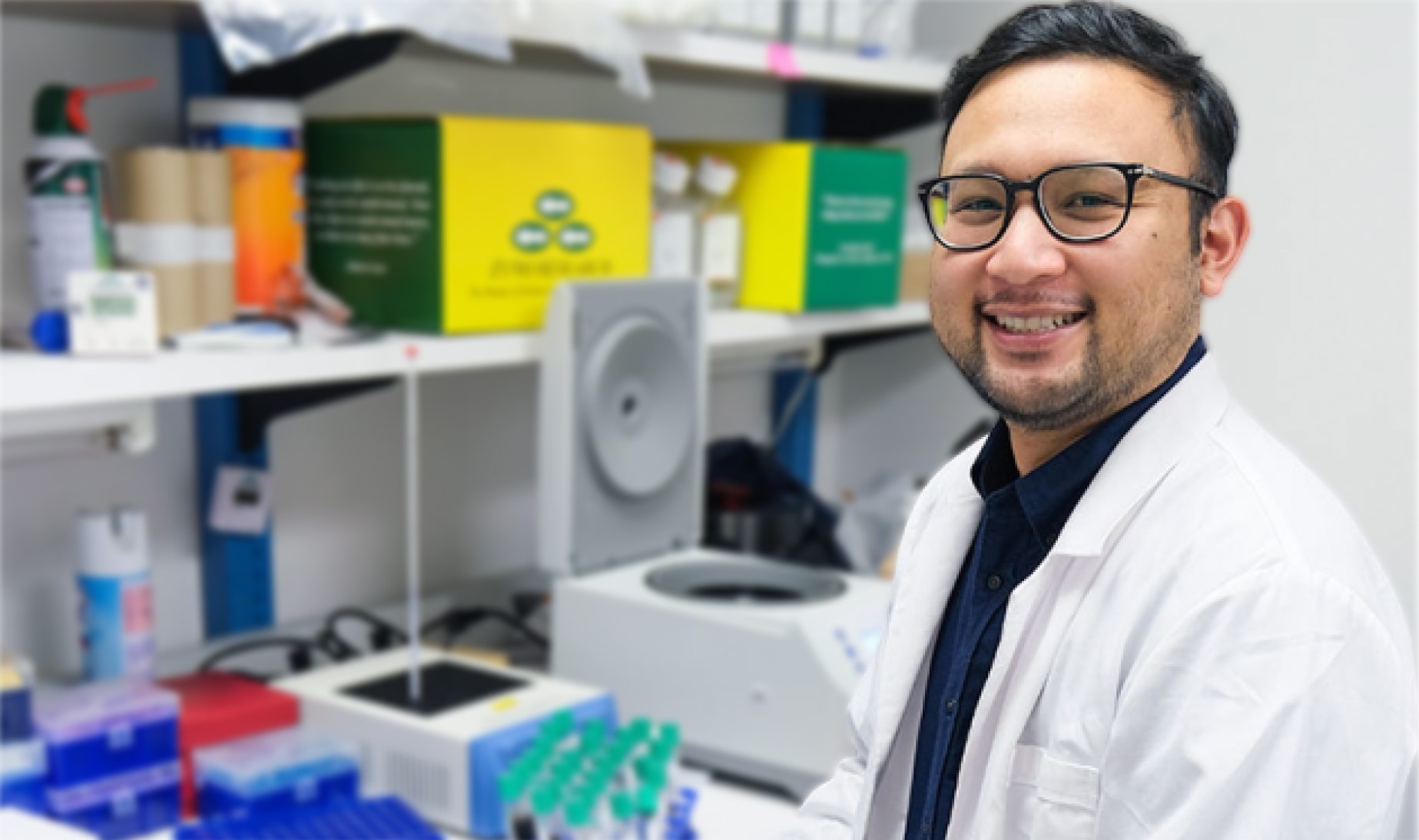 A scientist working at the bench, smiling at the camera