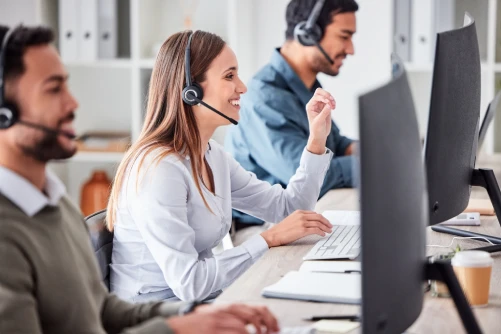 Persons with headsets in call center providing support via phone in front of a computer