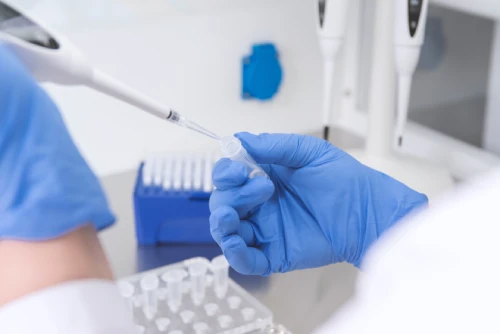Scientist pipetting at lab bench with many instruments around her