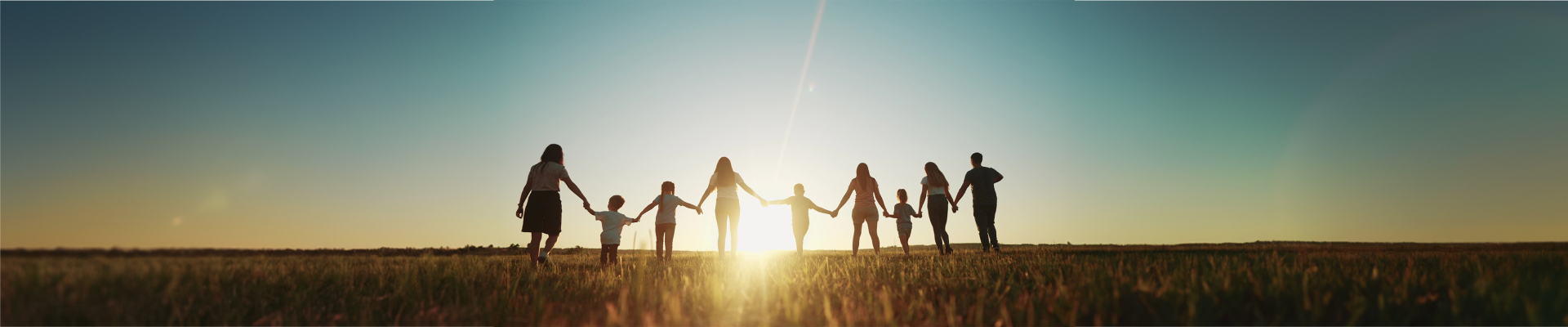 Banner image of adults and children holding hands and walking away from the camera towards the sunlight