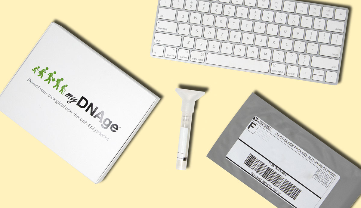 Image of a keyboard, a booklet of myDNAge, a mailing envelope, and the SafeCollect Saliva Test Collection Kit