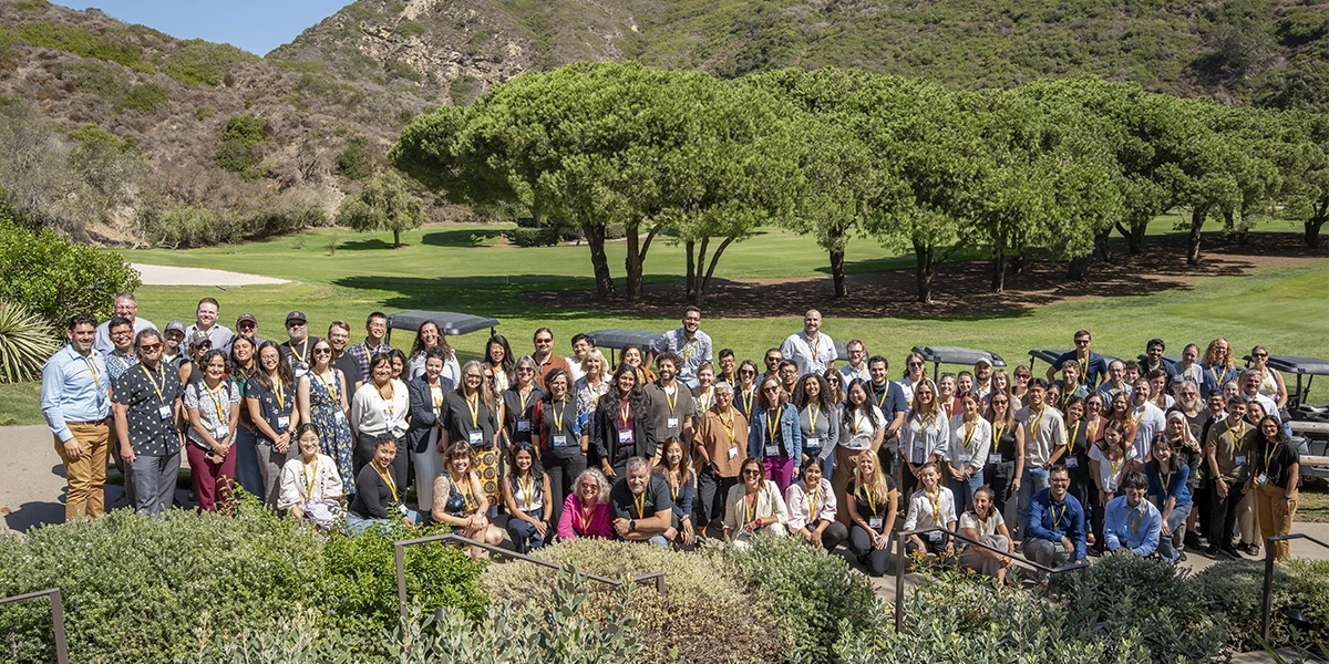 Symposium attendees gather in front of a grassy golf course